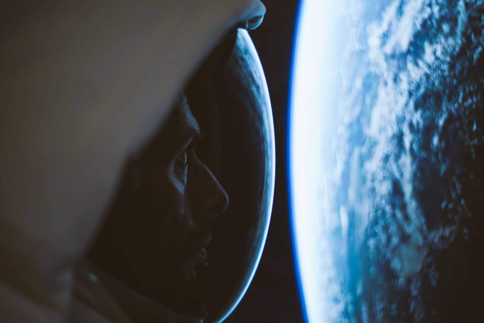 A man in a space suit looking at Earth from space