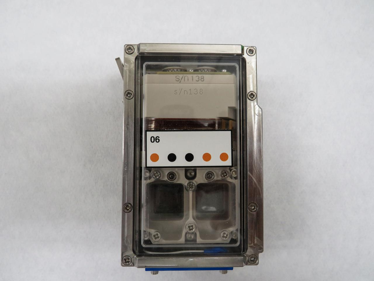 Metallic rectangular device with transparent cover showing components, labeled 06 with status dots